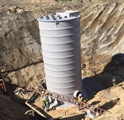 Workers digging and installing a wetwell manhole